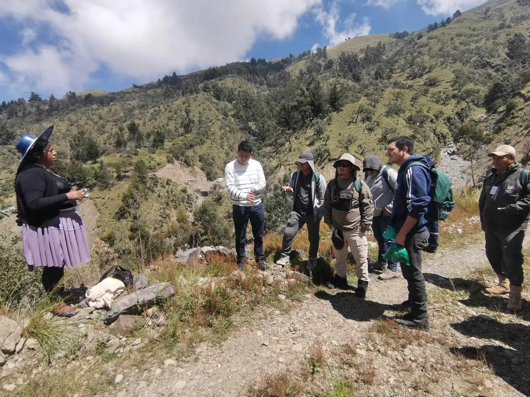 Lideresa comunitaria de pollera expone ante el grupo CERT reunido al borde de la quebrada andina